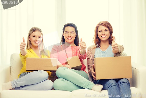 Image of smiling teenage girls with cardboard boxes at home