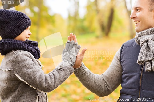 Image of happy father and son making high five in park