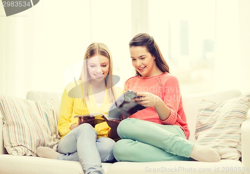 Image of two girlfriends reading magazine at home