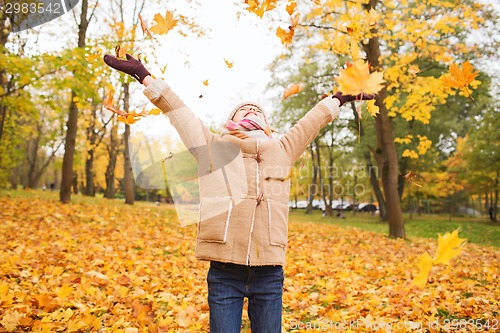 Image of smiling little girl with autumn leaves in park