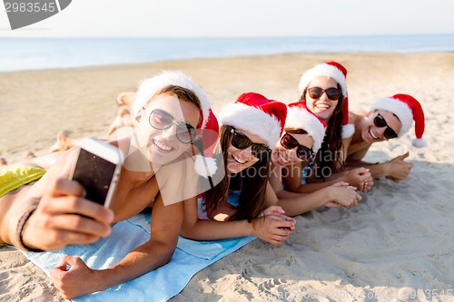 Image of group of friends in santa hats with smartphone