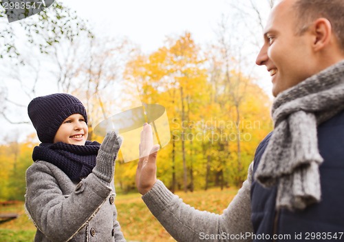 Image of happy father and son making high five in park