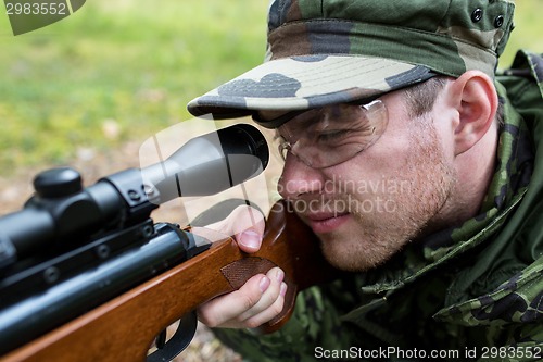 Image of close up of soldier or hunter with gun in forest