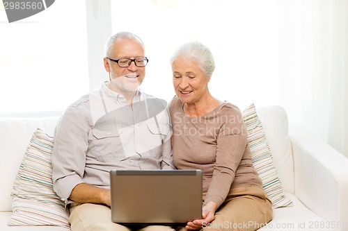 Image of happy senior couple with laptop at home