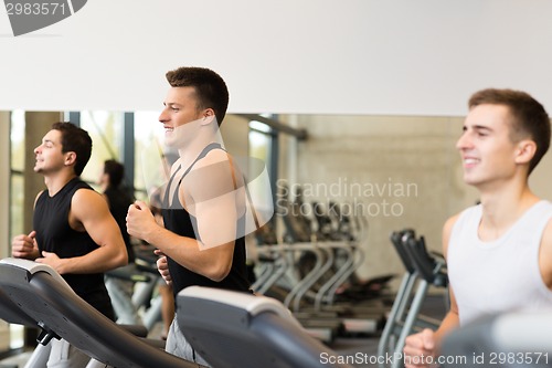 Image of smiling men exercising on treadmill in gym