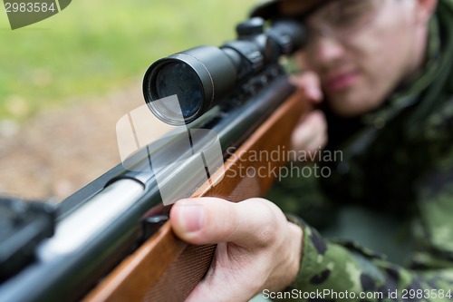 Image of close up of soldier or hunter with gun in forest