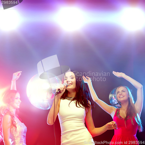Image of three smiling women dancing and singing karaoke