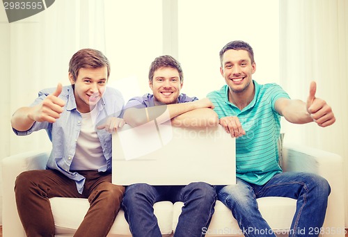 Image of smiling male friends holding white blank board