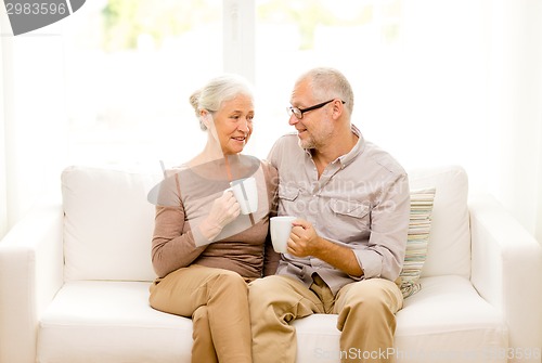 Image of happy senior couple with cups at home