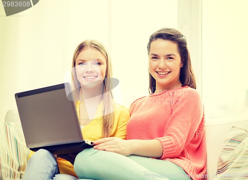 Image of two smiling teenage girls with laptop at home