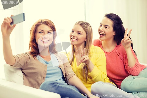 Image of smiling teenage girls with smartphone at home