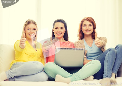 Image of three smiling teenage girls with laptop at home