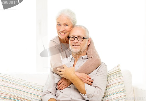 Image of happy senior couple hugging on sofa at home