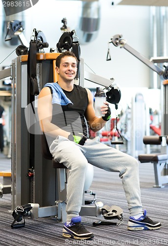 Image of smiling man exercising on gym machine