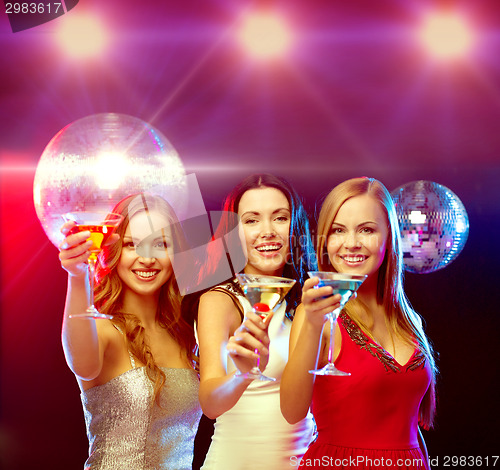 Image of three smiling women with cocktails and disco ball