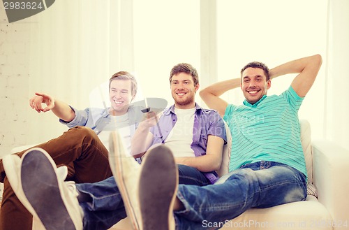 Image of smiling friends with remote control at home