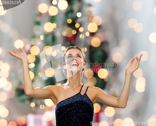 Image of smiling woman raising hands and looking up