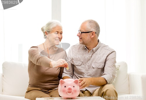 Image of senior couple with money and piggy bank at home