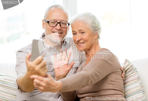 Image of happy senior couple with smartphone at home