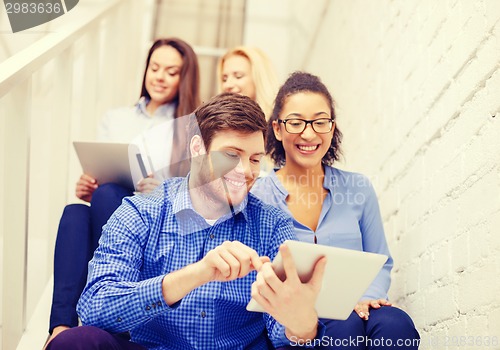 Image of team with tablet pc computer sitting on staircase