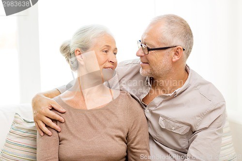 Image of happy senior couple hugging on sofa at home