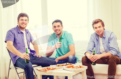 Image of smiling friends with beer and pizza hanging out