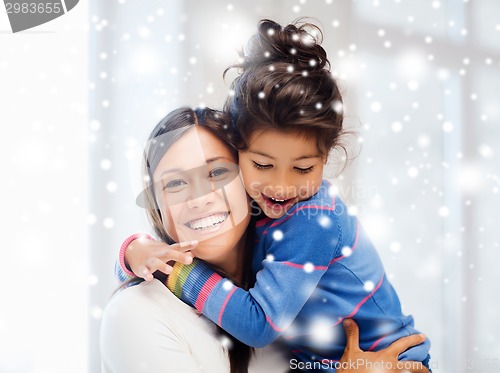 Image of smiling little girl and mother hugging indoors