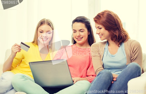 Image of smiling teenage girls with laptop and credit card