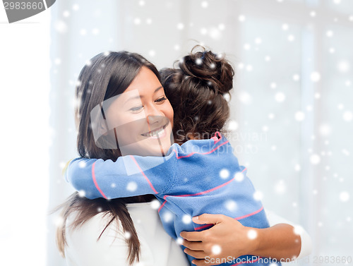 Image of smiling little girl and mother hugging indoors