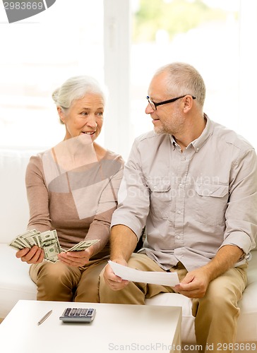 Image of senior couple with money and calculator at home