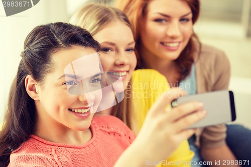 Image of smiling teenage girls with smartphone at home
