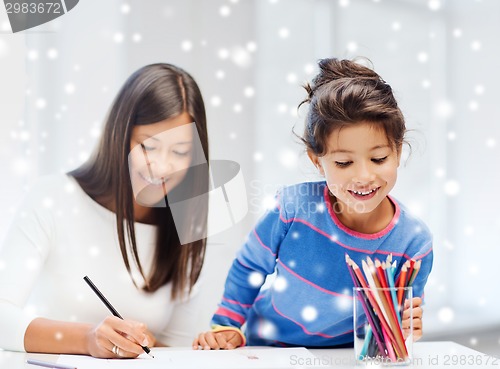 Image of mother and daughter with coloring pencils indoors