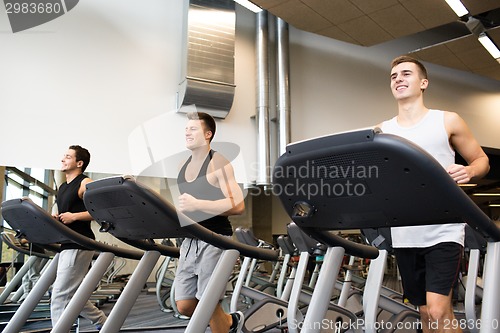 Image of smiling men exercising on treadmill in gym