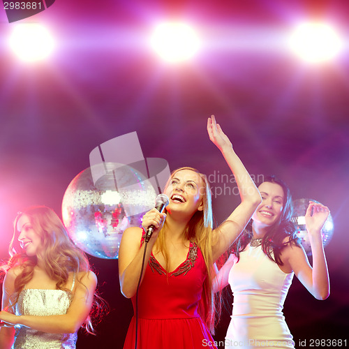 Image of three smiling women dancing and singing karaoke