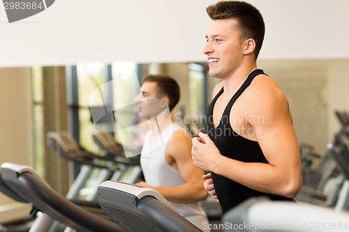 Image of smiling men exercising on treadmill in gym