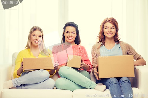 Image of smiling teenage girls with cardboard boxes at home