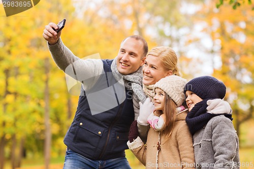 Image of happy family with camera in autumn park