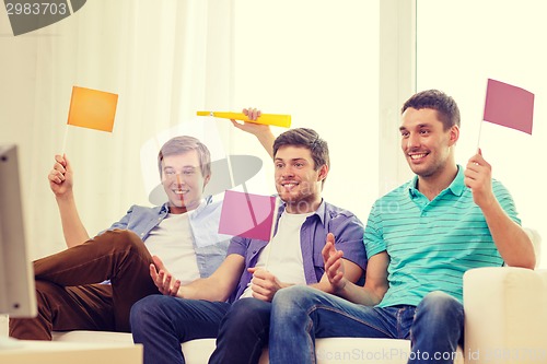 Image of happy male friends with flags and vuvuzela