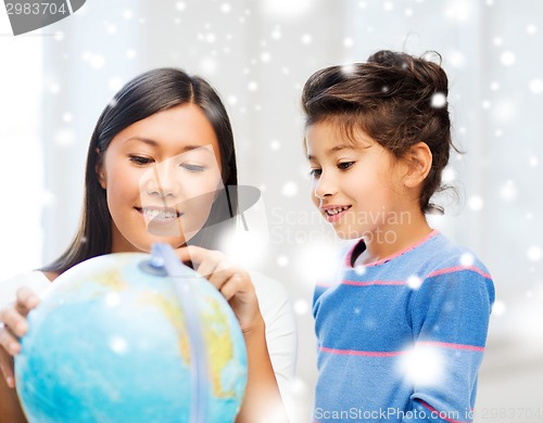 Image of mother and daughter with globe indoors