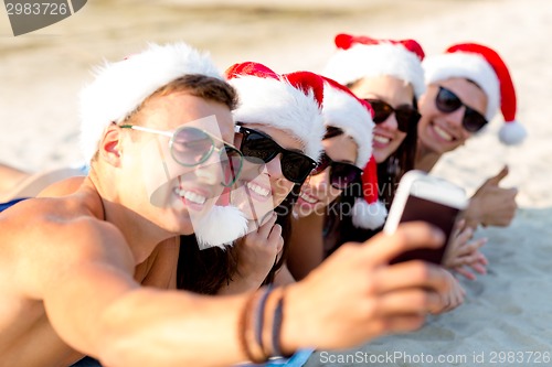 Image of group of friends in santa hats with smartphone