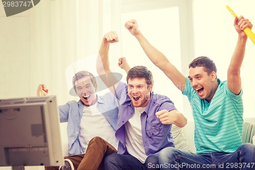 Image of happy male friends with vuvuzela watching sports