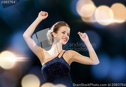 Image of smiling woman dancing with raised hands