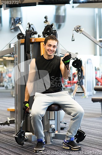 Image of smiling man exercising on gym machine
