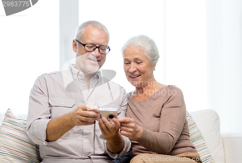 Image of happy senior couple with camera at home