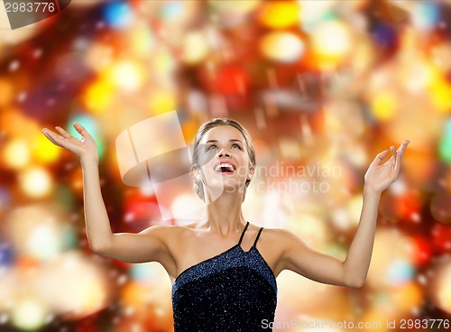 Image of smiling woman raising hands and looking up