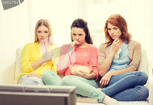 Image of three sad teenage girl watching tv at home