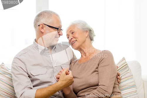 Image of happy senior couple hugging on sofa at home