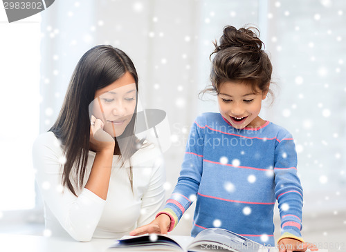 Image of mother and daughter with book indoors