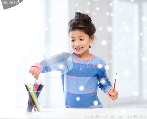 Image of smiling little girl with pencils drawing at home