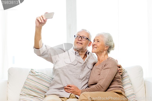 Image of happy senior couple with smartphone at home